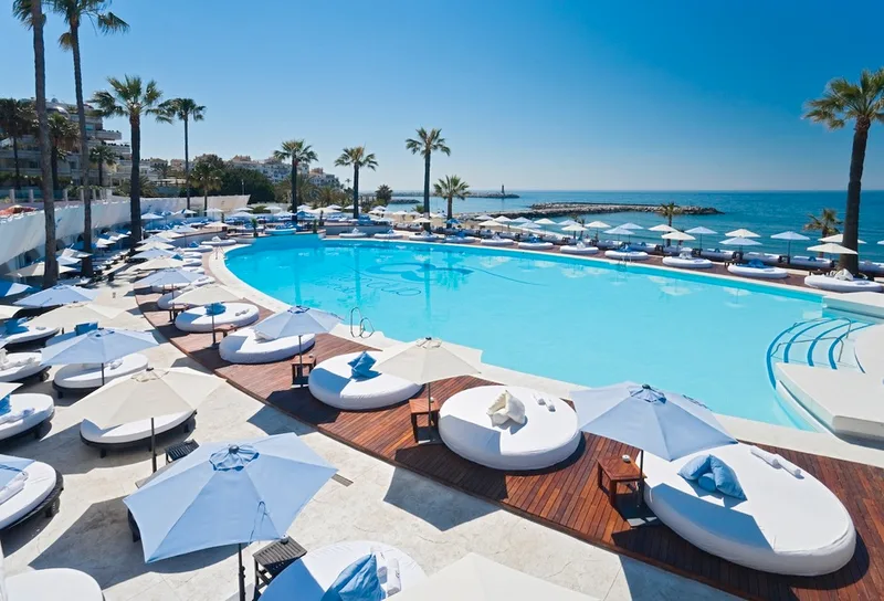 Ocean Club Marbella saltwater pool with white sunbeds and guests