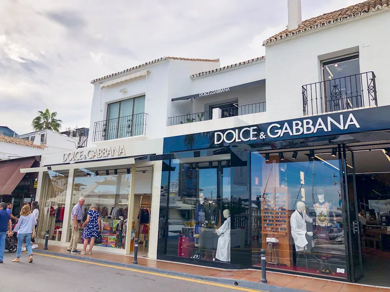 Puerto Banus designer shopping strip with Dolce and Gabbana boutique and yachts behind