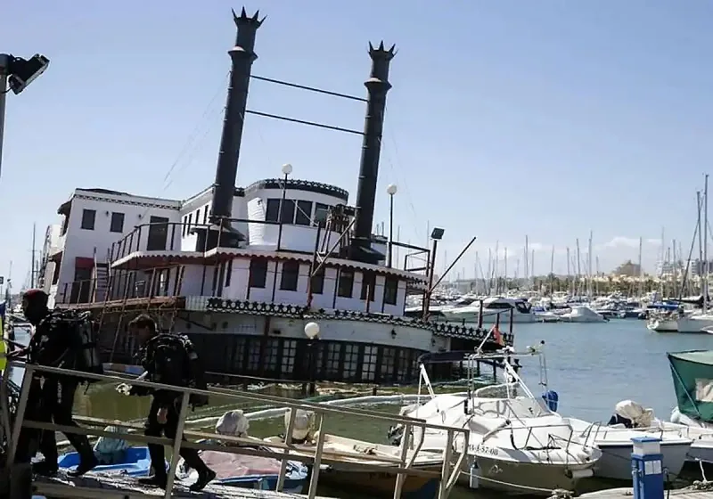Mississippi Willow derelict American paddle steamer moored in Benalmadena Puerto Marina inner harbour, rusting wooden hull and faded lettering visible